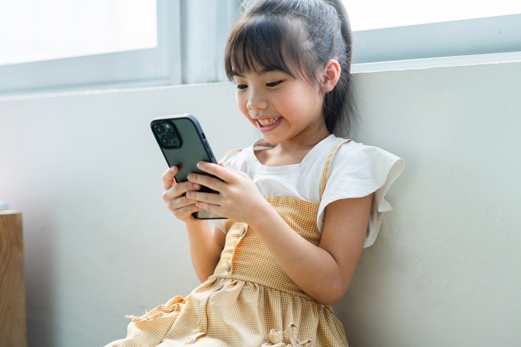 Asian Child Using Smartphone at Home